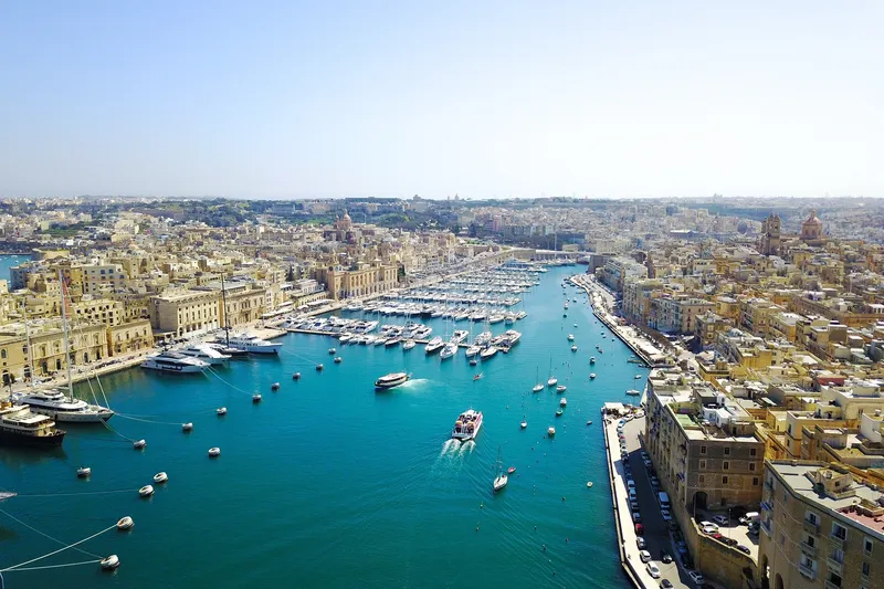 Aerial view of boats across Malta's Grand Harbour beneath Valletta and the Three Cities