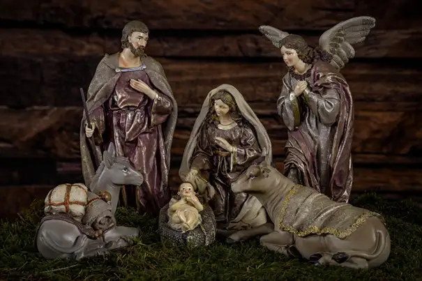Maria und Josef sowie ein Engel bewundern den kleinen Jesus im Stall zu Bethlehem