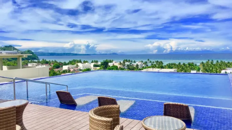 Spacious open-air swimming pool with distant sea view on the top floor of the hotel at Altabriza Resort Boracay