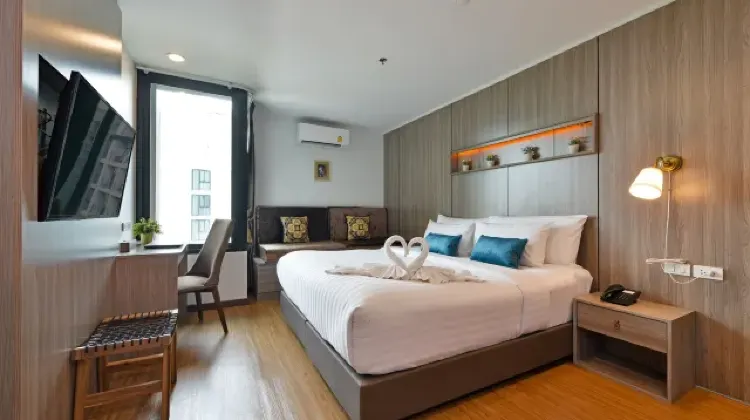 Neat hotel room with bed, table, chairs and TV at Bedever Bangkok Boutique Hotel