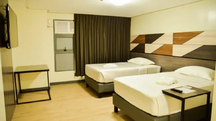 Simple hotel room with two beds, desk and TV at Travelite Hotel Legarda