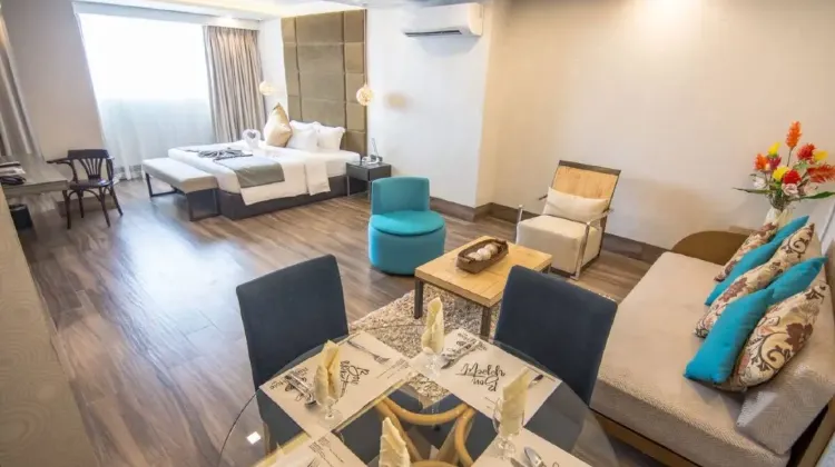 Warm and comfortable hotel room with sofa, table, chairs and bed at Goldberry Lite Hotel