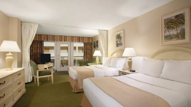 Clean hotel room with two beds, table, chairs and TV at Quality Inn Oceanfront
