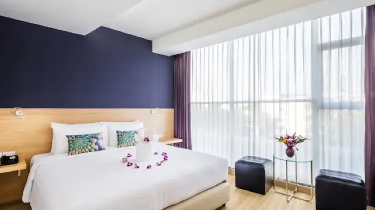 Neat hotel room with bed, table, chairs and TV at Solo Express Sukhumvit 81