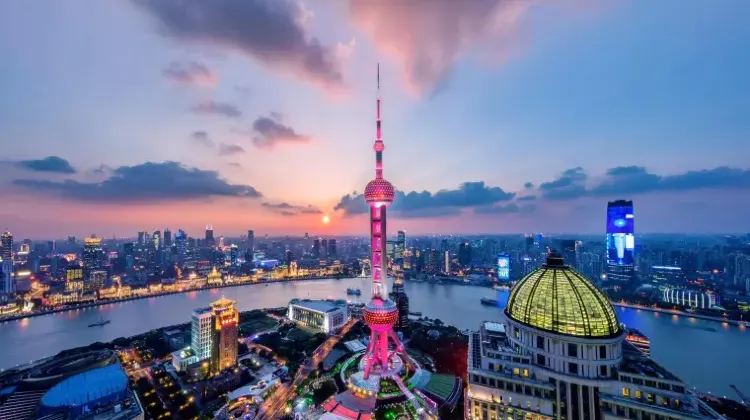 夕焼けに照らされる上海の東方明珠タワーと外灘の夜景。黄浦江の両岸に高層ビルが立ち並ぶ景観。
