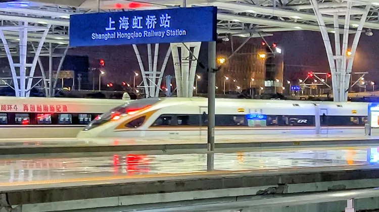 夜の上海虹橋駅ホームに停車する高速鉄道CRH列車。駅名標が見える上海主要鉄道駅の風景。
