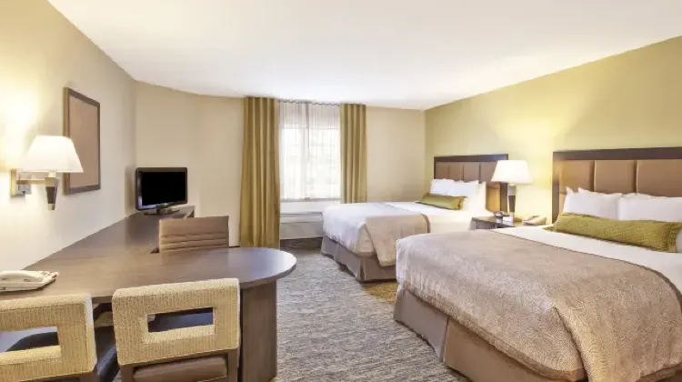 Spacious hotel room with two beds, table, chairs and TV at Candlewood Suites Indianapolis Airport