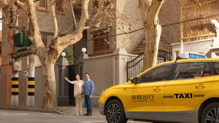 上海の住宅街でタクシーを利用する人々と、黄色い上海タクシー。街路樹のある静かな通りの風景。