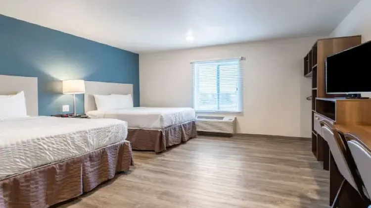 Bright hotel room with two beds, table and chairs at WoodSpring Suites Indianapolis Castleton