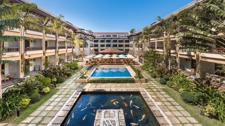 Outdoor swimming pool surrounded by greenery and hotel building exterior at Henann Regency Resort and Spa