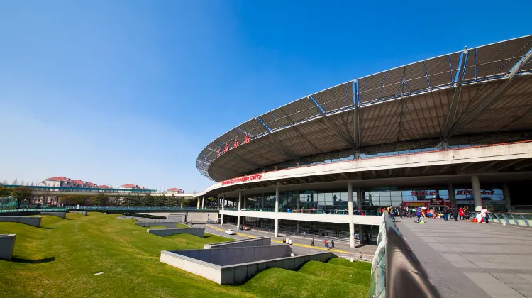 上海南駅の外観。丸い屋根とガラス張りのデザインが特徴の近代的な駅舎と広場の風景。