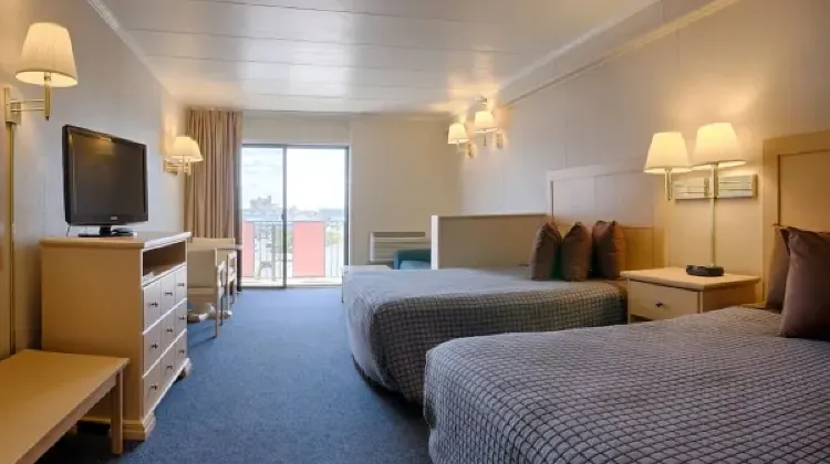 Cozy hotel room with two beds, table, chairs and TV at Flamingo Motel