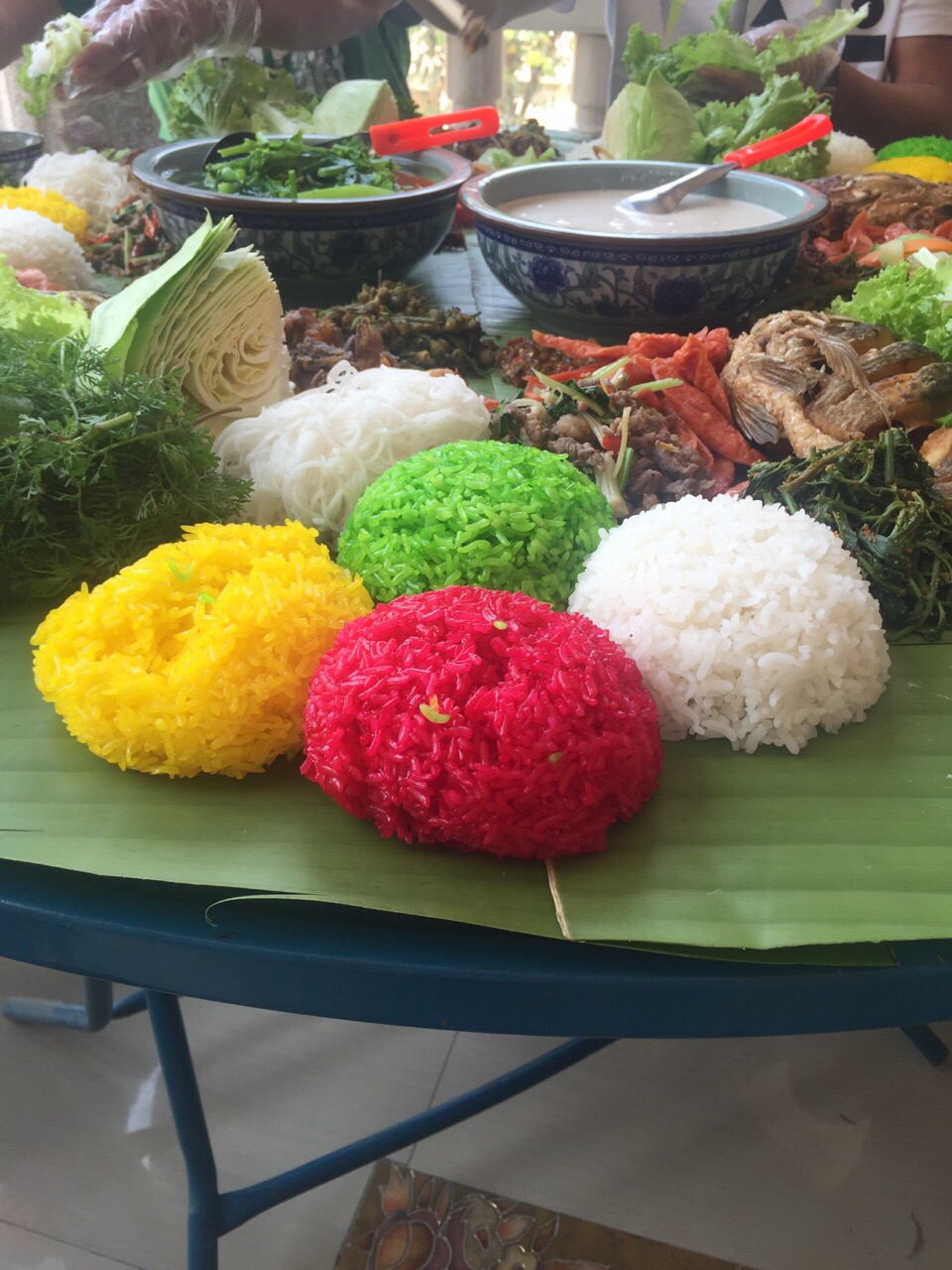 缅甸佤邦第一特区佤王宴，饭色全用可食野生植物汁液染成，伴烤鱼、生菜等用手抓吃，其中一盒白色的汤是秘密