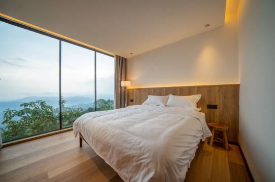 Guest room with floor-to-ceiling windows and mountain views at Yishan Tea Garden