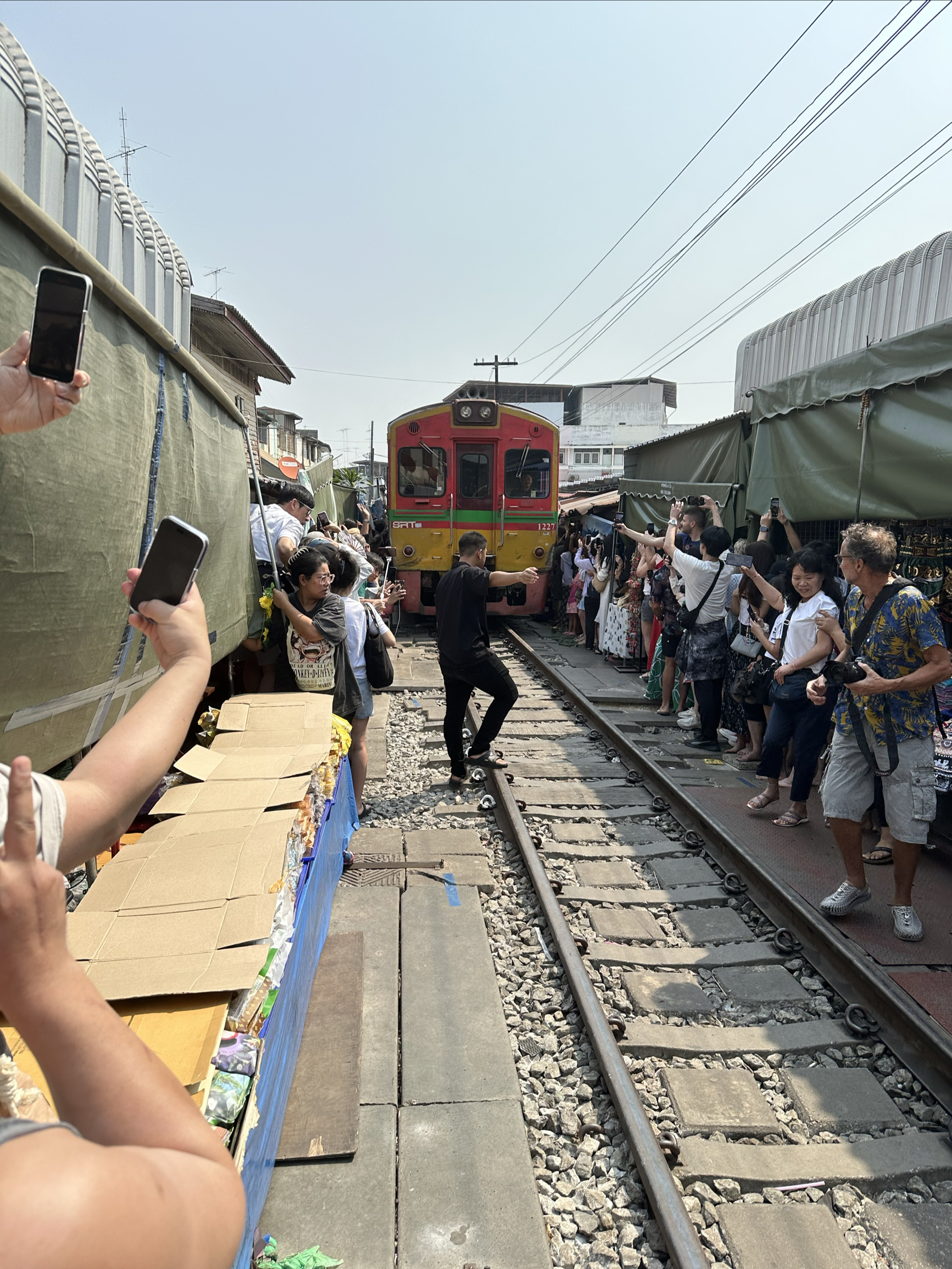 泰国美攻铁路市场，火车轨道两侧人山人海，火车是寸步难行