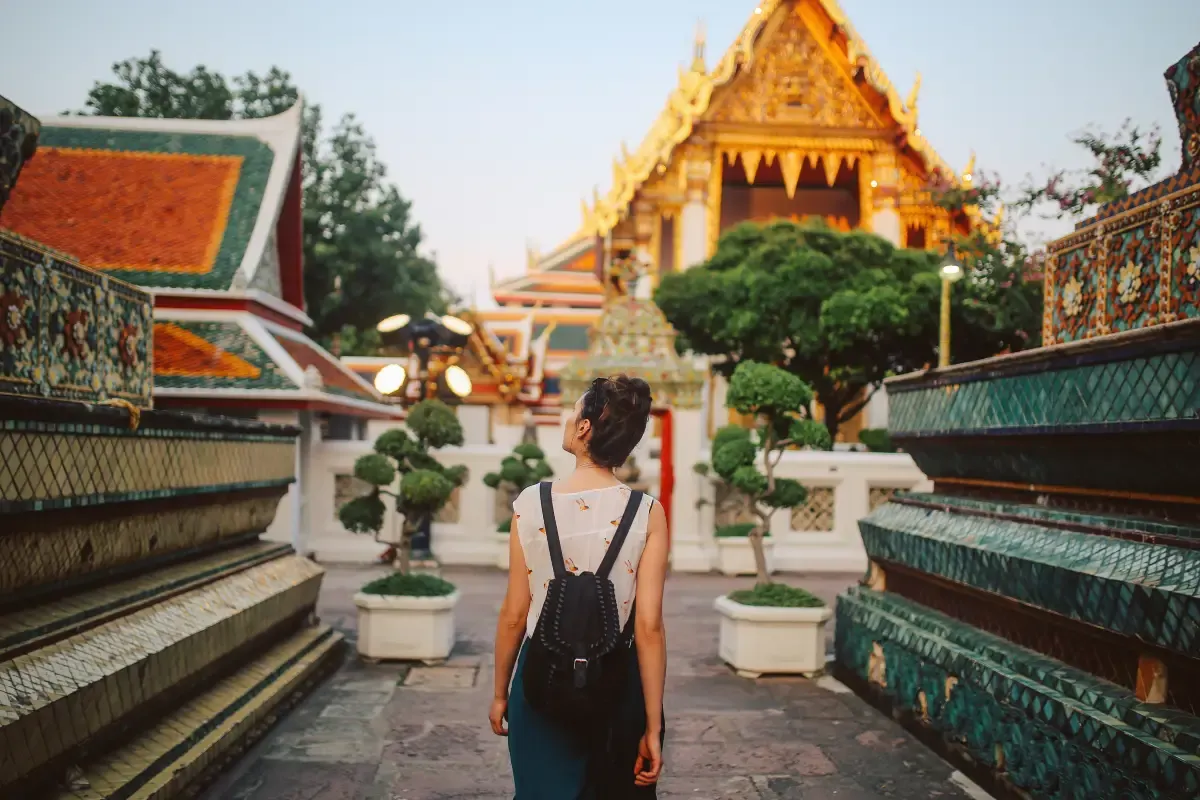 A tourist with a backpack, walking through a corridor within the ancient and mysterious temples of Bangkok
